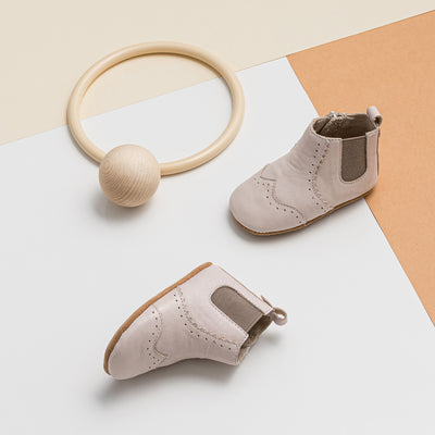 Pair of baby windsor boots in colour Stone next to wooden toy