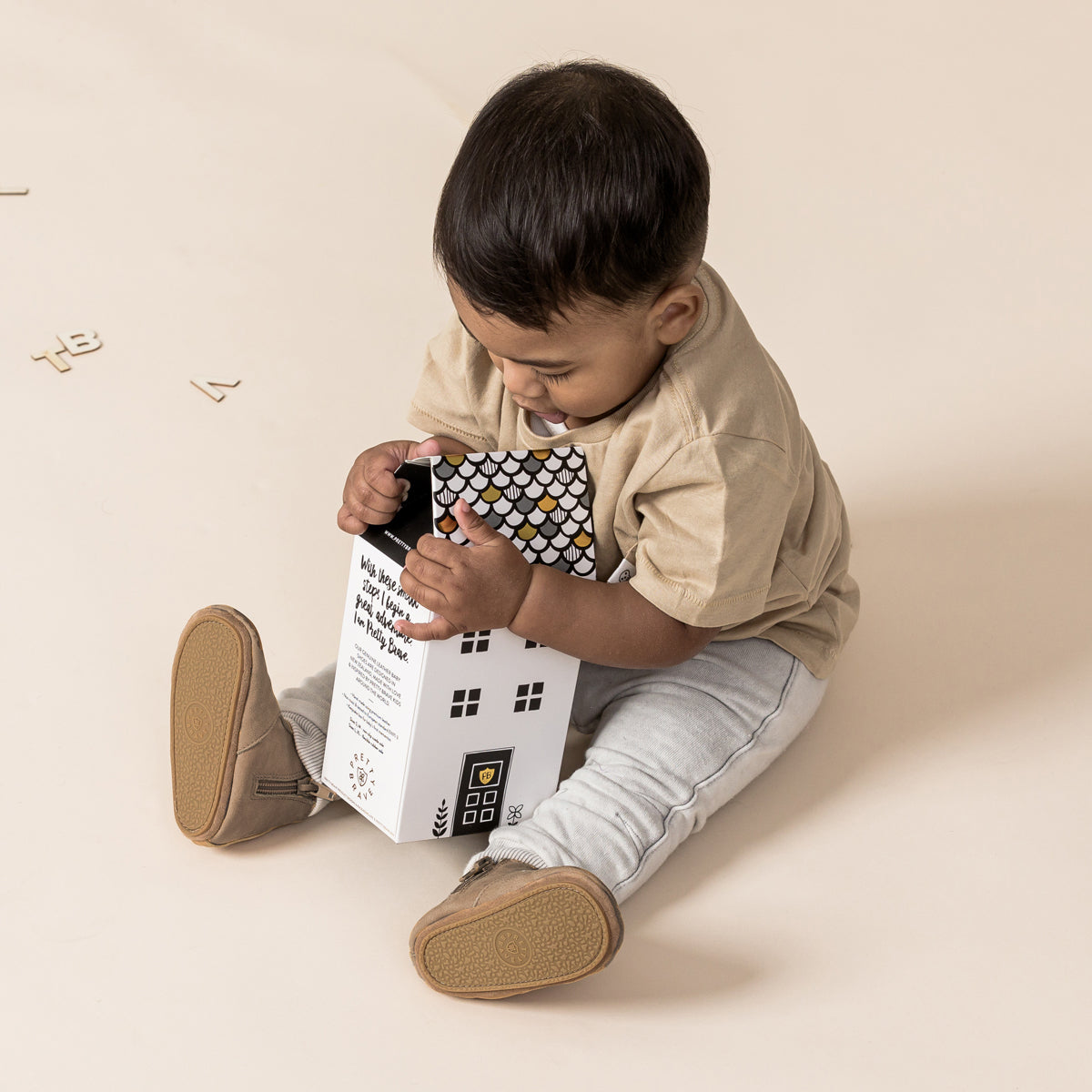 Baby playing with box wearing baby electric boots in colour taupe