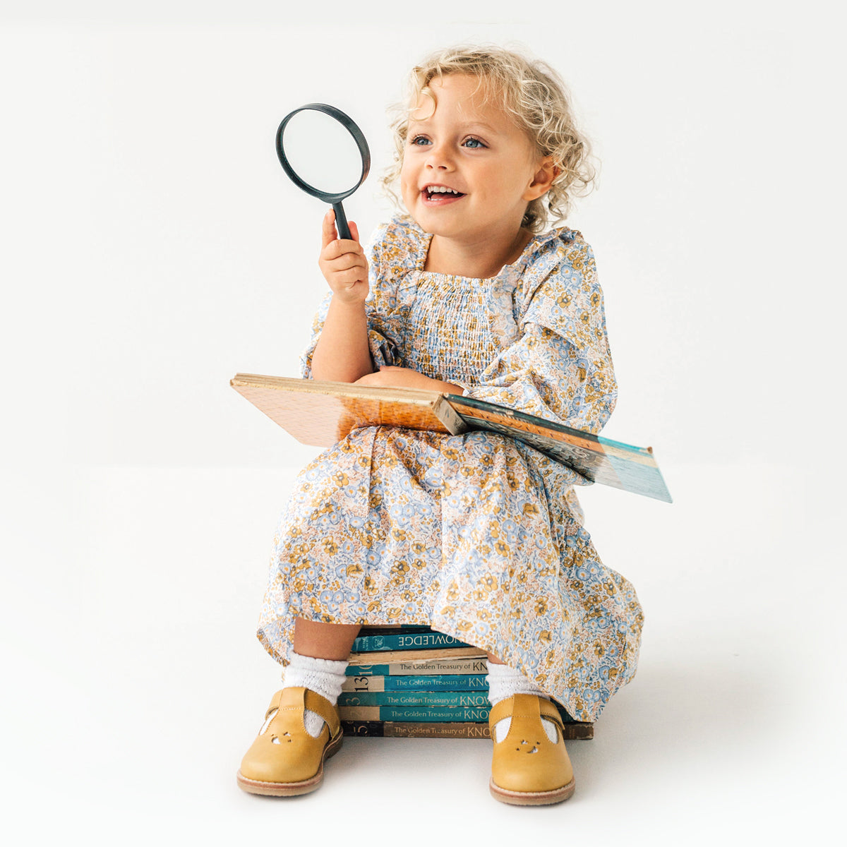 Toddler playing with book wearing Amelia sandals in colour honey