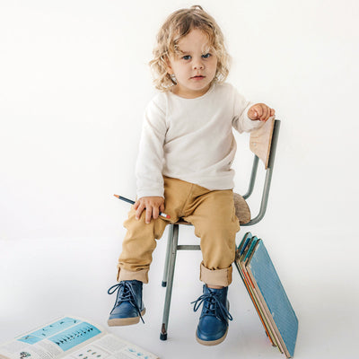 Child sitting on chair wearing Archie boot in midnight blue colour