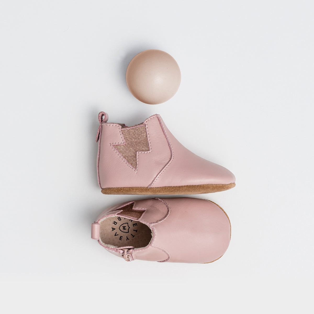Pair of baby boot in colour blush with lightning detail next to wooden ball