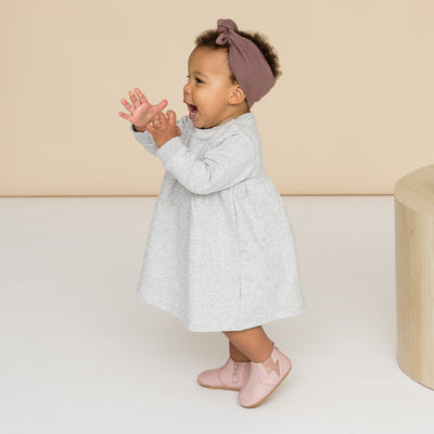 Happy toddler wearing baby boot in colour blush with lightning detail
