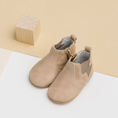 Pair of baby electric boots in colour sand next to wooden cube