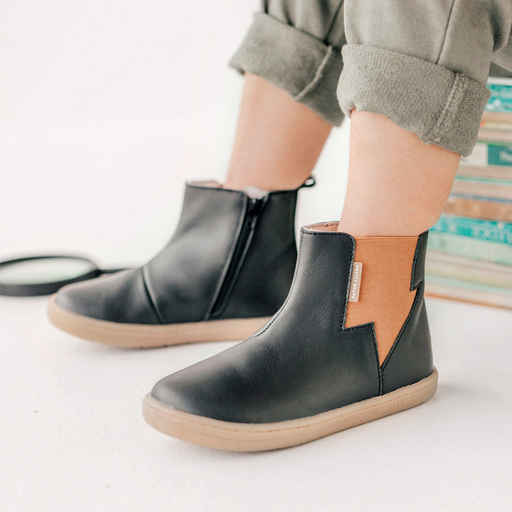 Child wearing lightning detail boot in colour black.
