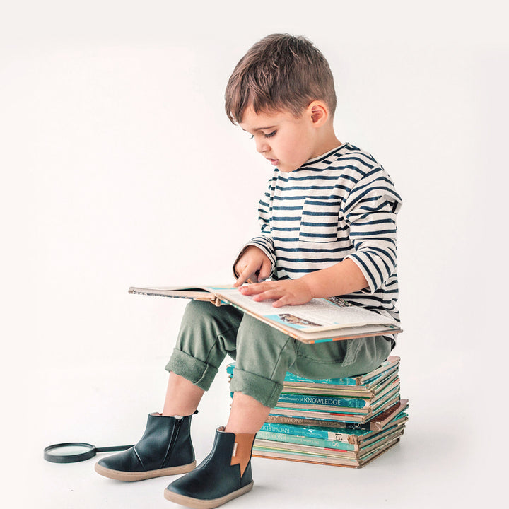 Child reading a book wearing lightning detail boot in colour black.