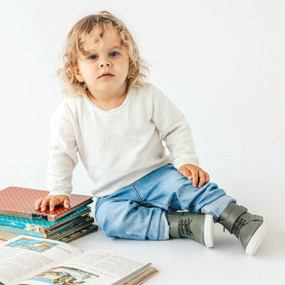 Toddler sitting on ground wearing Harley ankle boot in colour olive