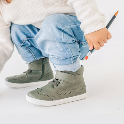 Toddler wearing jeans in Harley ankle boot in colour olive