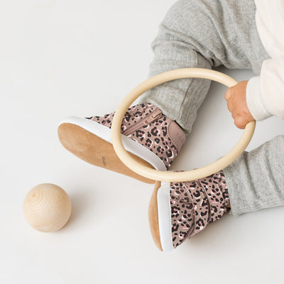 Toddler wearing Hi Top shoe in leopard print lpaying with wooden toy