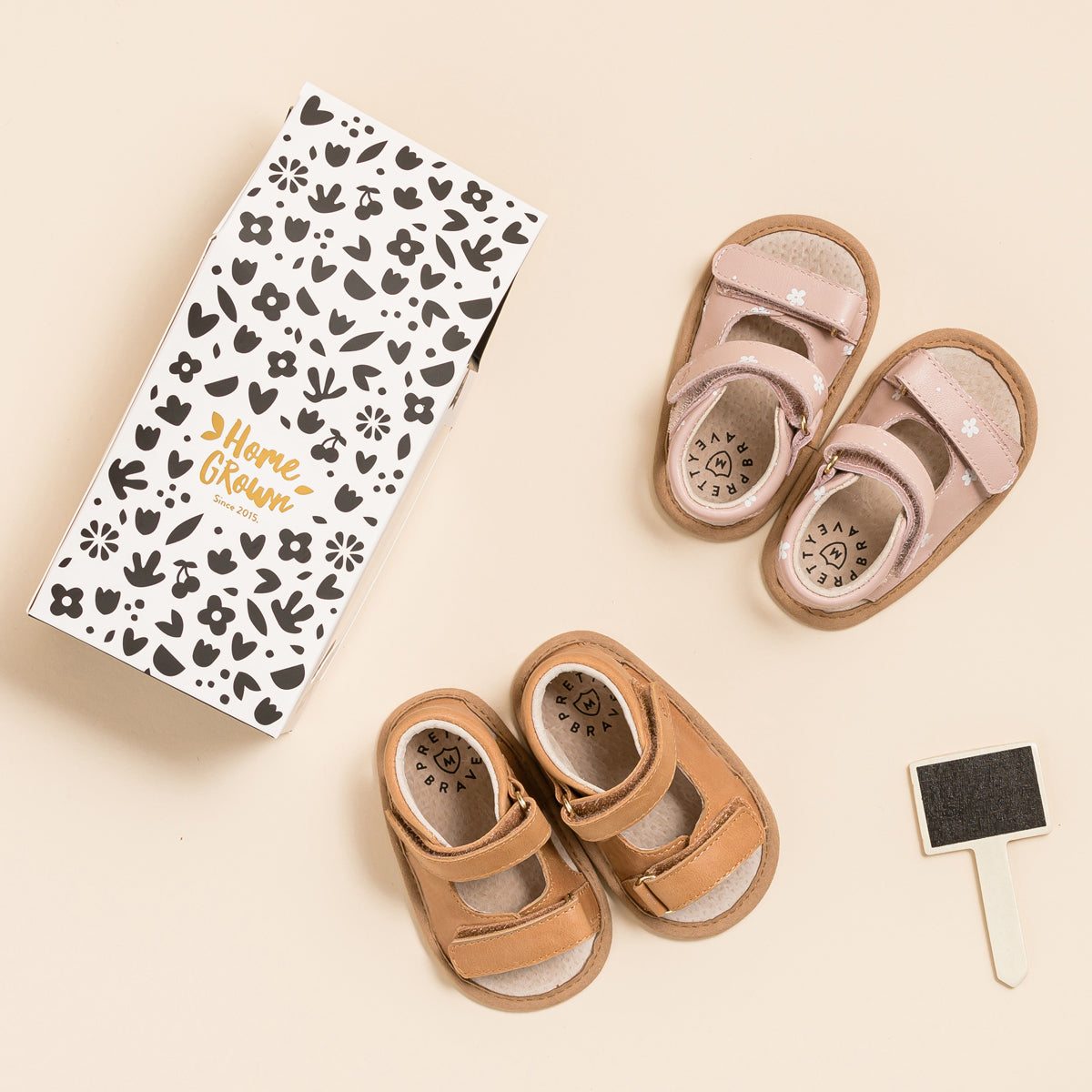 Two pairs of baby sandals next to cardboard box
