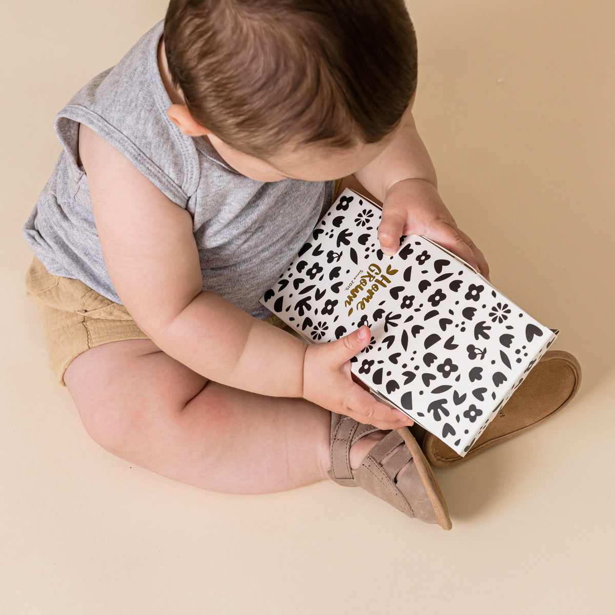 Bay playing with box wearing Charlie sandal in Taupe colour
