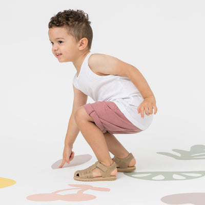 Child pointing at ground wearing Frankie sandals in colour Tan