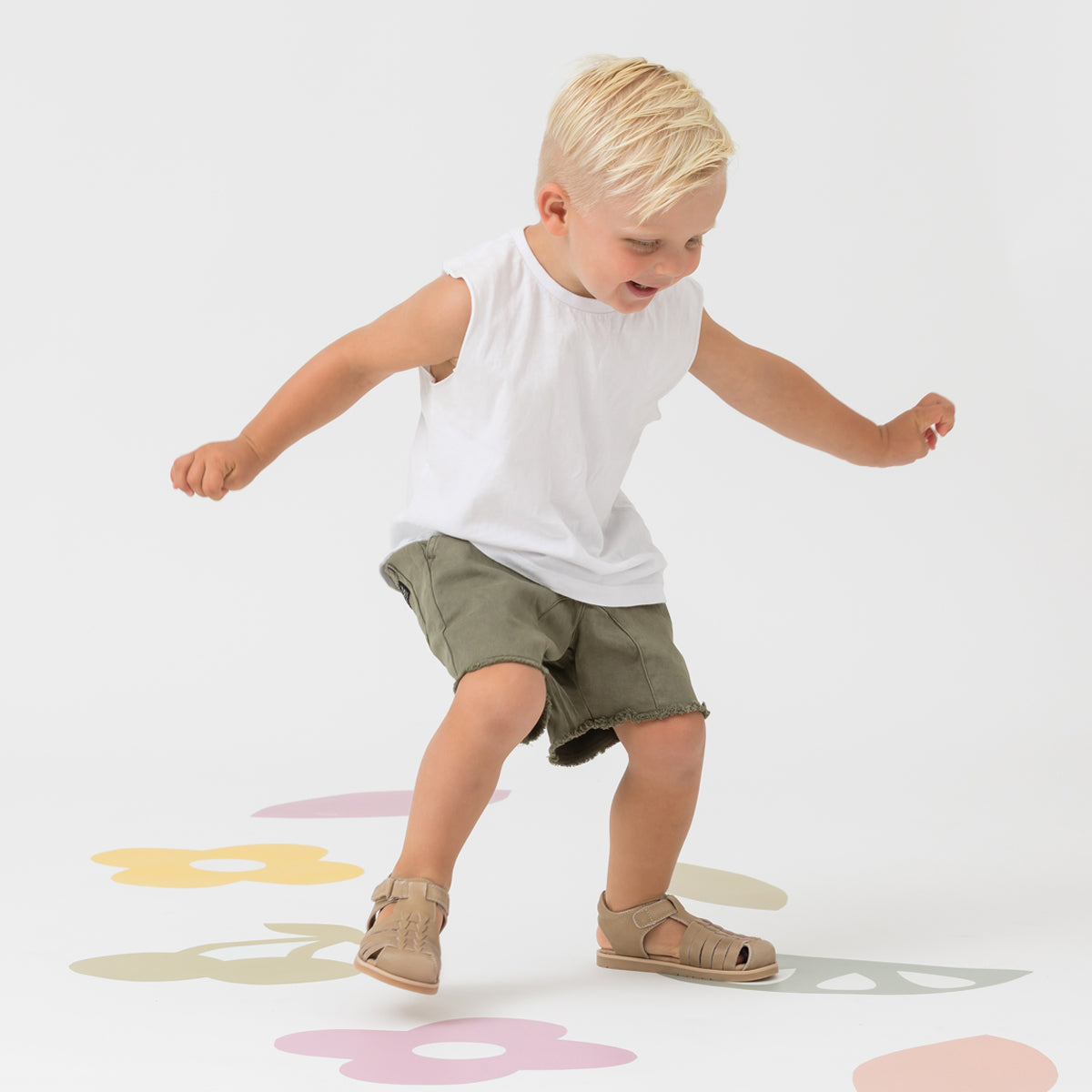 Child jumping wearing Frankie sandals in colour Tan