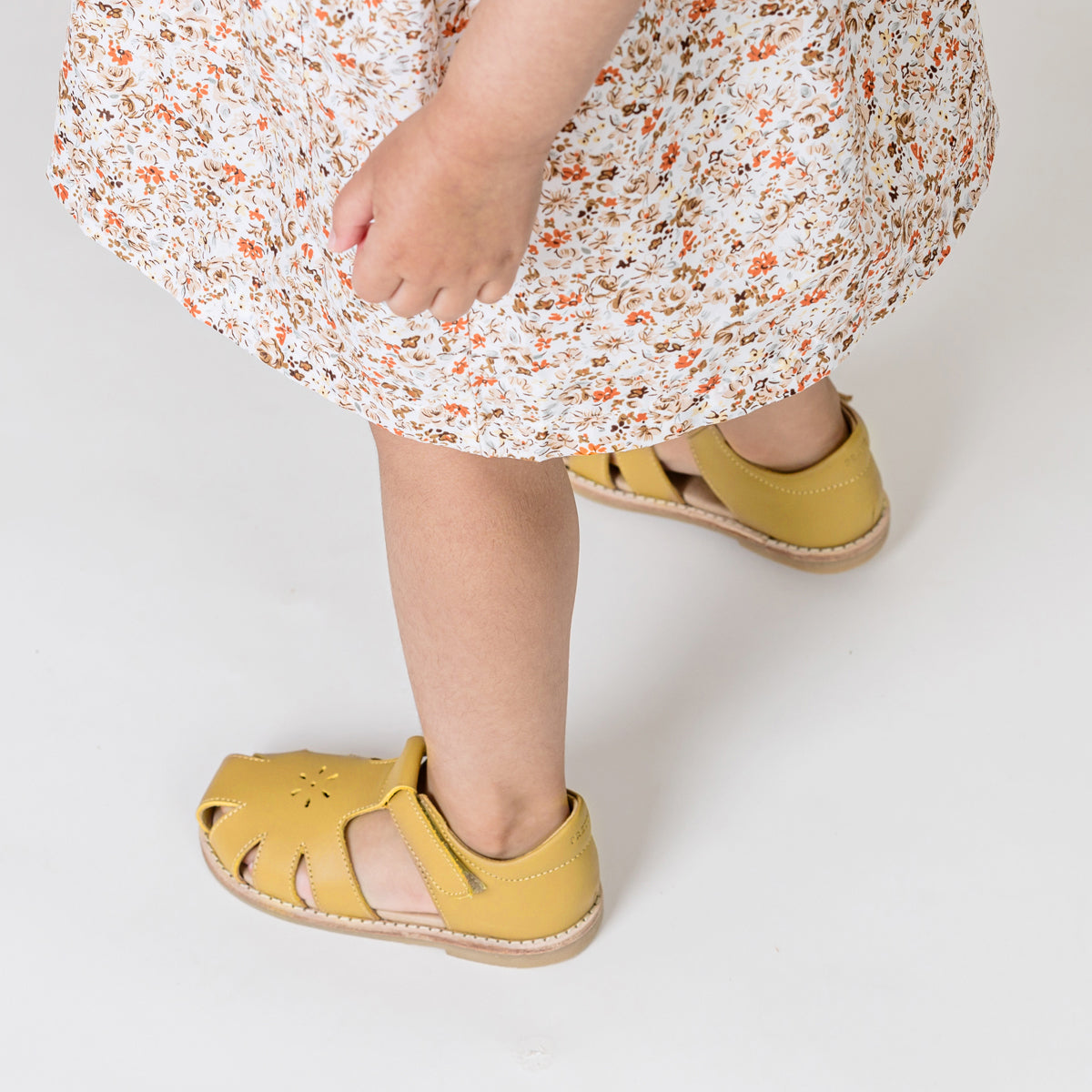 Toddler wearing Macy T-Bar shoes in honey colour and flower dress