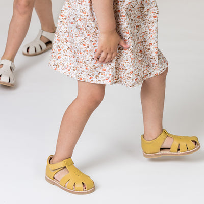 Toddler wearing Macy T-Bar shoes in honey colour. 